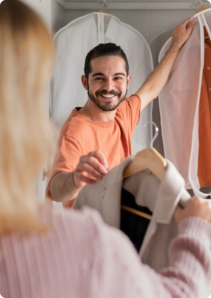 professional laundry service guy hanging cloths in wardrobe