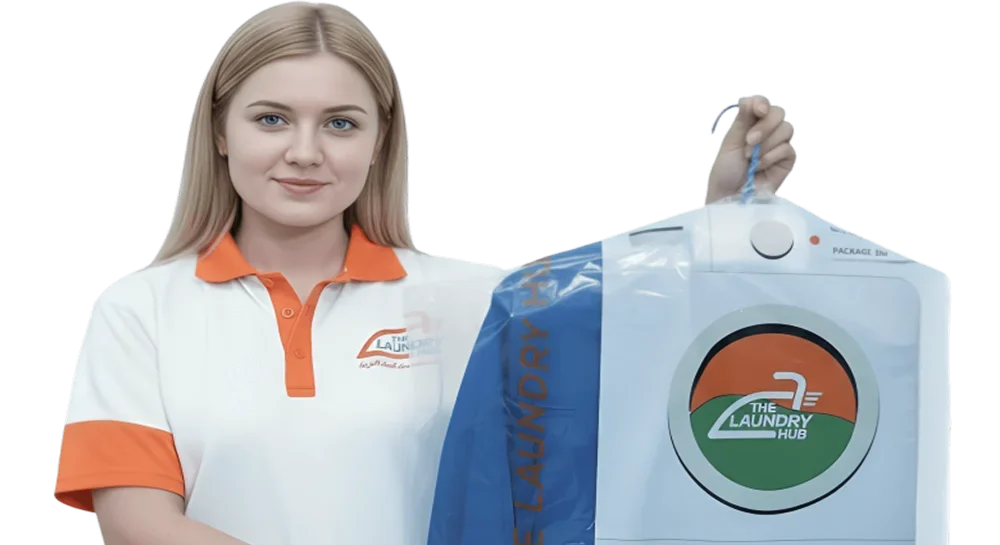 lady worker at laundry hub showing clean cloths neatly ironed and packed under plastic cover on a hanger